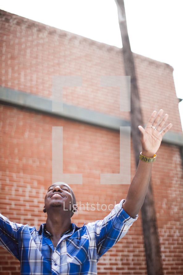 an African-American man with hands raised in worship 