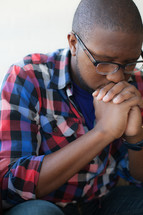 African-American man with head bowed and praying hands 