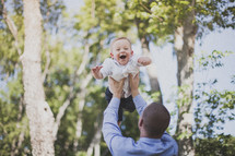 man lifting his toddler son in the air
