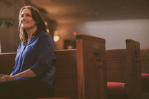 woman sitting in a pew in a church smiling 