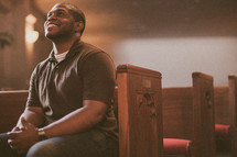 man sitting in a church looking up to God 