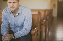 man sitting in a pew in a church in prayer 