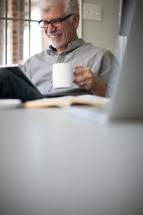 man looking at an iPad screen and drinking a cup of coffee 