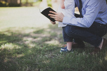 father reading a Bible to his son