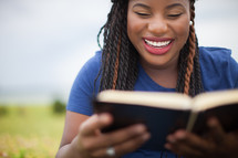 smiling woman reading a Bible outdoors 