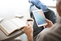 man looking at an iPad screen and an open Bible 