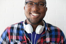 face of a man wearing reading glasses and headphones around his neck with a beard 