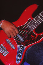 African American man's hand on a red electric guitar 