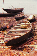 Wooden row boats on the shore of a lake.