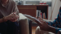 Female therapist writing down some notes on clipboard, having conversation with patient during counseling session. Cropped shot
