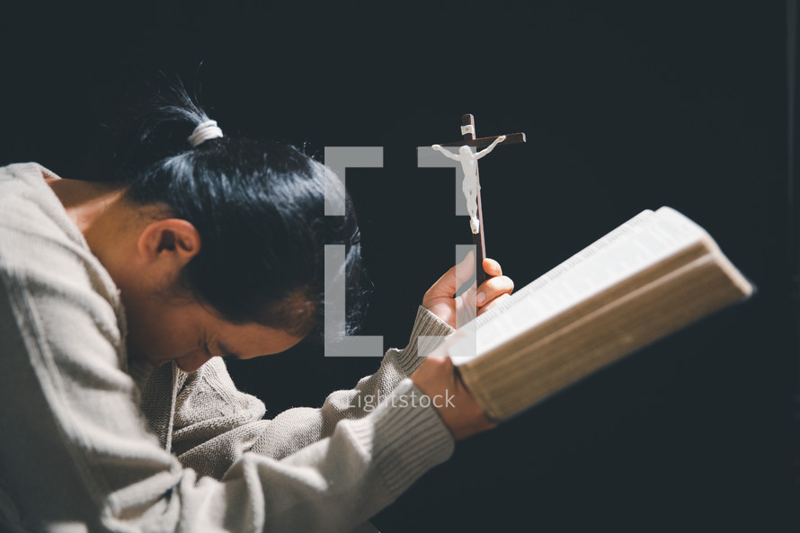 Asian woman holding a crucifix and Bible
