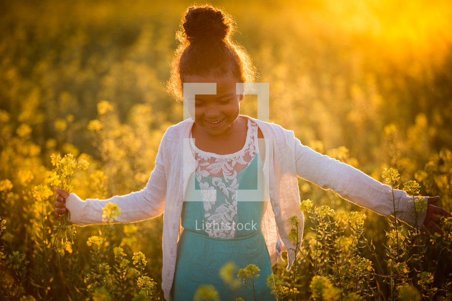 a little girl walking through a field of yellow flowers 