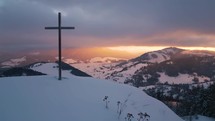 Light of sun in winter countryside nature with steel cross religious christian symbol in snowy hill at sunrise Aerial view 
