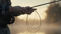 Young fly fisherman casting on a foggy river at sunrise