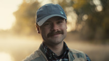 A Smiling young fly fisherman on a foggy river at sunrise