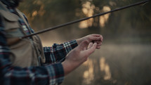 Young fly fisherman casting on a foggy river at sunrise