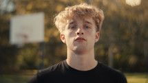 Portrait of a smiling young man playing basketball on a sunny day