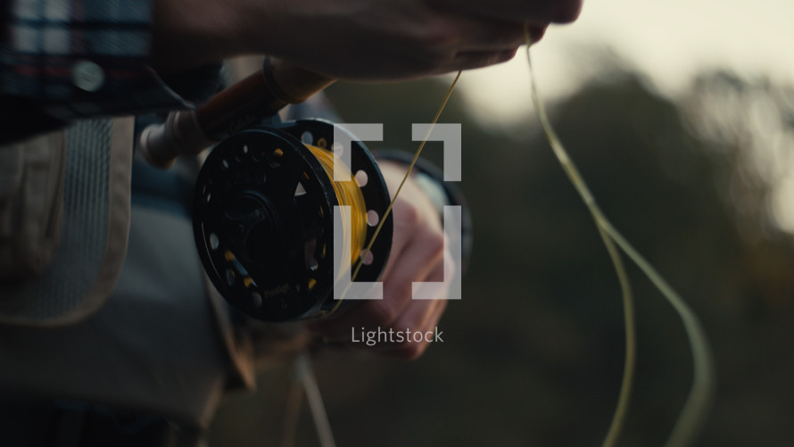 Young fly fisherman casting on a foggy river at sunrise