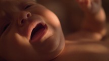 Slow motion close-up shot of three months baby crying. Indoor shot with sun light on the child face
