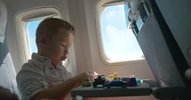 Little kid playing with toy cars in the airplane