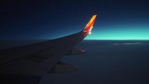 Airplane wing flying at sunrise
