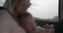 Mother and son using mobile phone during car ride