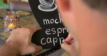 Man writing coffee types on the chalk board