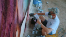 Street artist painting colorful graffiti on generic wall - Modern art concept with urban guy performing and preparing live murales with red aerosol color spray. Slow motion.