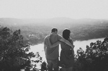 couple holding each other enjoying a view of a river