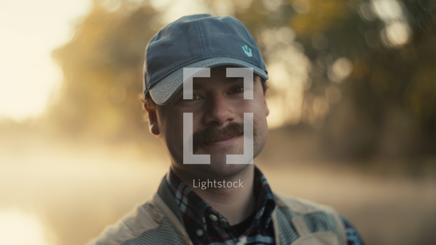 A Smiling young fly fisherman on a foggy river at sunrise