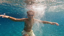 Underwater view of boy in goggles making bubbles