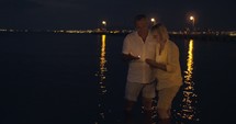 Mature couple making candles float in sea at night