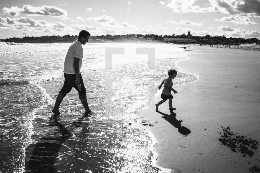 Father and son playing by water at the beach.