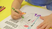 toddler boy coloring a coloring page with crayons at Sunday School 