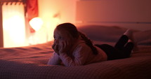 girl watching tv on a bed 