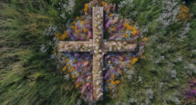 Wooden cross from an aerial perspective with wildflowers surrounding