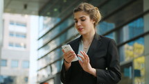 Young business woman walking on the street talking on her mobile phone