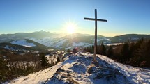 Winter nature panorama sun rays on blue sky steel cross with religious christian background