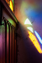 colorful sunlight on a wall through a stained glass window 