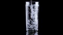 Effervescent tablet falling in a glass of water in slow motion on black background. Taking medication concept. Taking calcium, magnesium, vitamins, aspirin for a healthy life.