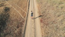 man flying a drone walking down a dirt road 