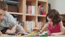 Two kids building with toy bricks at home