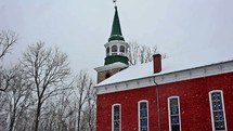 red church with steeple in the falling snow 