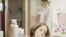 young girl brushing her teeth in front of the mirror