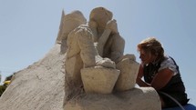 a man and woman carving a sand sculpture 