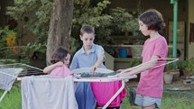 Three kids taking off laundry from the hanging line to the basket