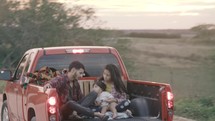 migrant family riding in the back of a truck on a dirt road 