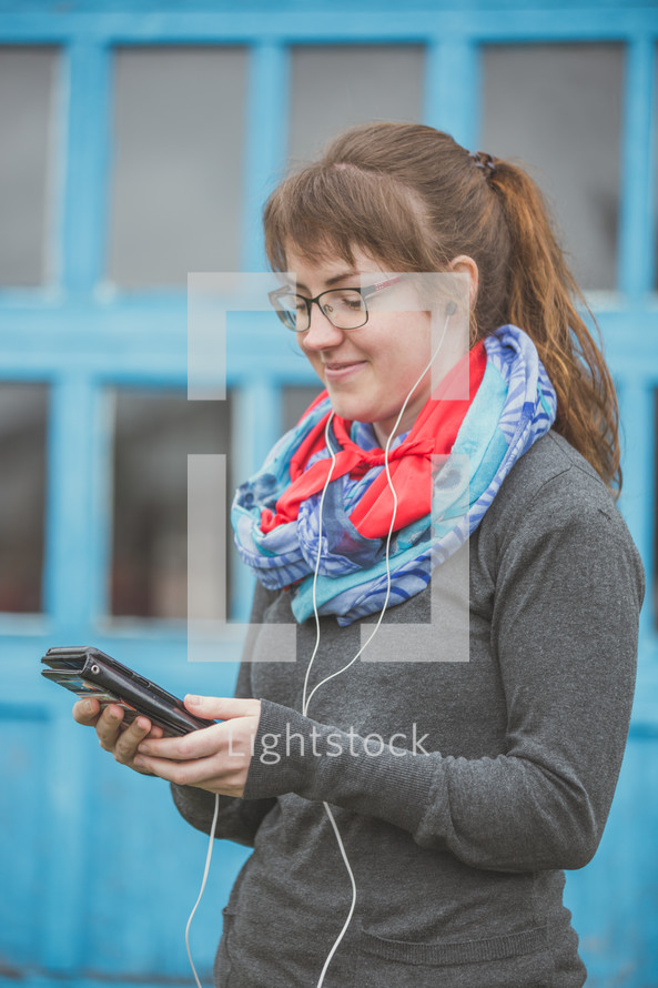 a woman listening to earbuds and holding a tablet 