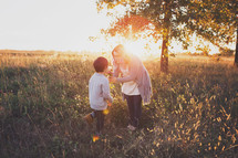 mother and son standing outdoors in a field 