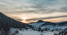 Golden Sunset Over Snowy Mountains With Dense Coniferous Forest During Winter. - Timelapse